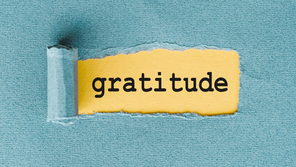 Gratitude Word Written on Yellow Paper Torn Through Blue Paper