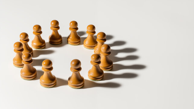 group of wooden chess pawns arranged in a circle on a white surface.
