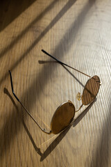 Elegant sunglasses on the wooden table in the sun light