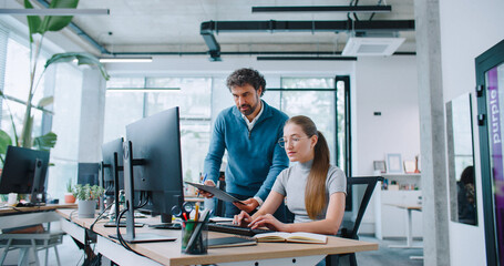 Attractive Caucasian leader controlling quality of work of his employee. Man comparing information...