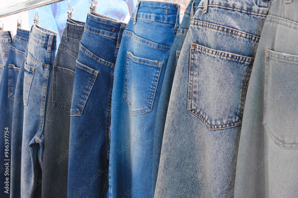 Poster a row of jeans hanging on a clothesline. the jeans are of different colors and styles. concept of va