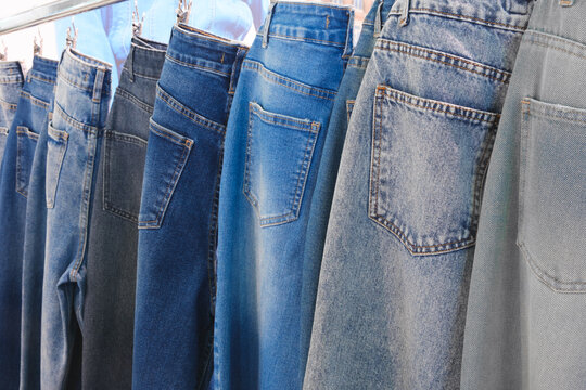 A row of jeans hanging on a clothesline. The jeans are of different colors and styles. Concept of variety and choice, as the person hanging the jeans can pick and choose which pair to wear