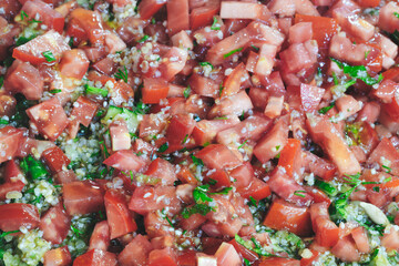A close up of a red tomato salad with parsley and other herbs. The salad is full of tomatoes and parsley, and it looks fresh and appetizing