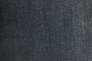 Macro closeup: dark blue denim fabric with intricate weave pattern and subtle variations in...