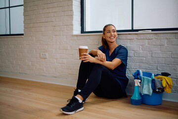 Happy housemaid drinking coffee while having  break at work.