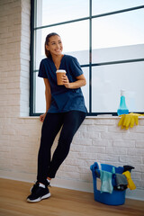 Happy woman having coffee break while working as professional cleaner.