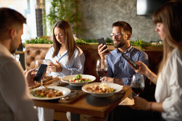 Group of business colleagues using their own cell phones  while having  a lunch in a restaurant.
