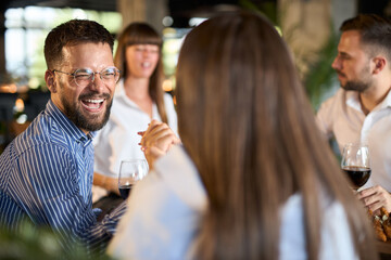 Happy entrepreneur talking to his colleagues during lunch break in restaurant.
