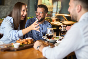 Group of happy business colleagues using cell phone during lunch in a restaurant