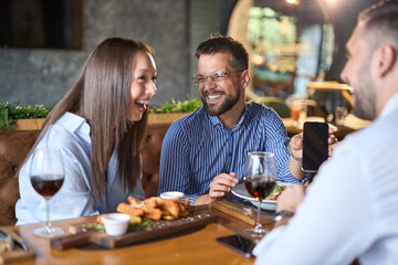 Group of happy business colleagues using cell phone during lunch in a restaurant