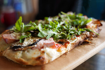 Traditional Italian pizza with arugula and tomatoes on a dark background.