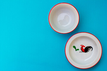 A collection of crockery sets made of porcelain in the blue background. The crockery has the image of a rooster.