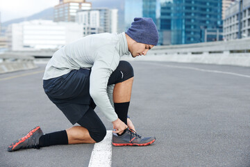 Runner, man or tie sneakers in city for morning jog, fitness or getting ready for cardio workout in street. Athlete, person or prepare running shoes on urban bridge for exercise, training or marathon