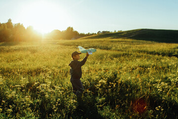 A little boy is playing outside with a toy airplane that he made himself. childhood, a dream of traveling, a rich fantasy