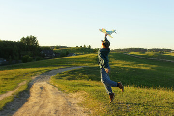 Fototapeta premium A little boy is playing outside with a toy airplane that he made himself. childhood, a dream of traveling, a rich fantasy