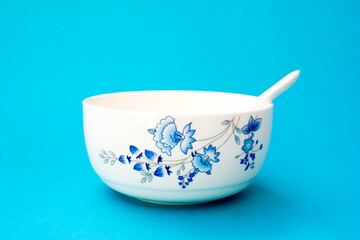 A bowl and spoon for eating soup or porridge. The bowl and spoon have a blue oriental floral motif.