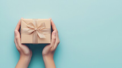 Hands Holding Gift Box with Bow on Blue Background