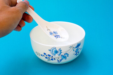 A bowl and spoon for eating soup or porridge. The bowl and spoon have a blue oriental floral motif.