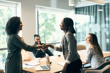 Happy business people, handshake or meeting with introduction, partnership or greeting at office. Young, employee or colleagues shaking hands for agreement, deal or teamwork together at workplace