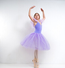 Young ballerina in a purple dress on a white background.