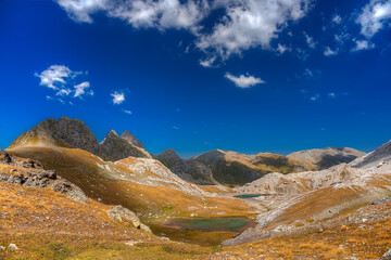 Fototapeta premium White clouds on a blue sky float over a mountain valley.