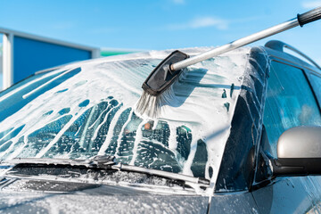 Washing Car Windshield Using Foam Brush on Sunny Day in a Car Wash