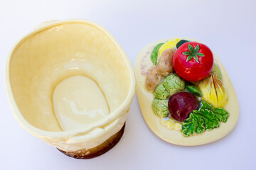 A fairly large container, made of brownish-beige porcelain. The lid has the shape of various fruits. This is a collection of old porcelain containers, used to contain fruits such as oranges, apples et