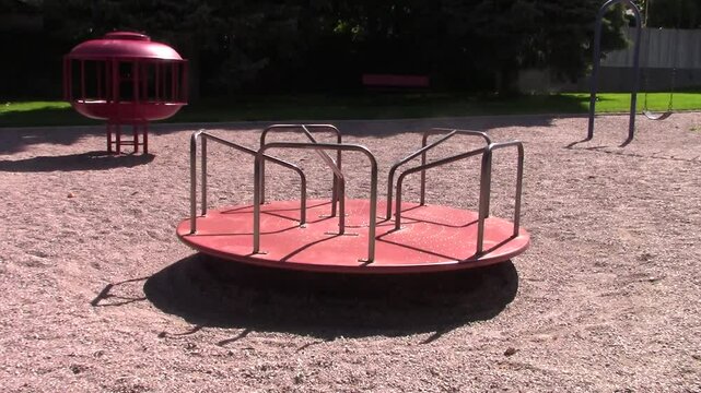 Classic merry-go-round carousel spinning with other playground equipment in background
