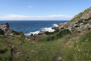 Unterhalb des Kullabergs brechen sich Wellen des Öresund an Felsen der Halbinsel Kullen. Gesehen an einem windigen und sonnigen Sommertag auf Kullen in der südschwedischen Provinz Schonen.