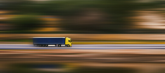 Banner with truck. A truck with a large semi-trailer is driving down the street. Speed blurred...