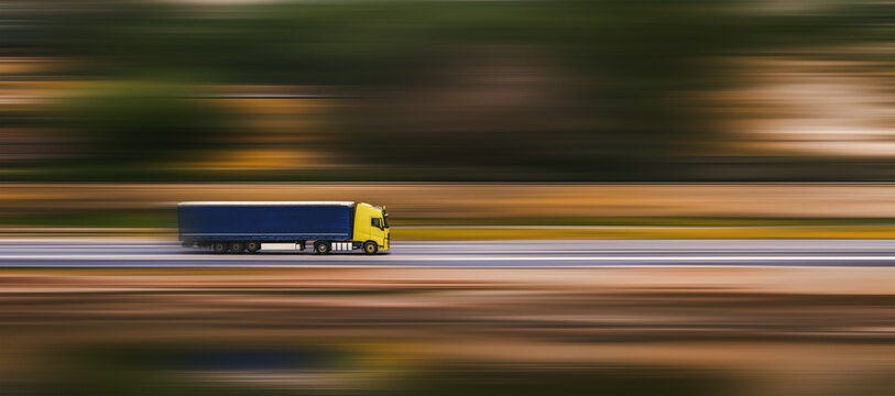 Banner with truck. A truck with a large semi-trailer is driving down the street. Speed blurred background