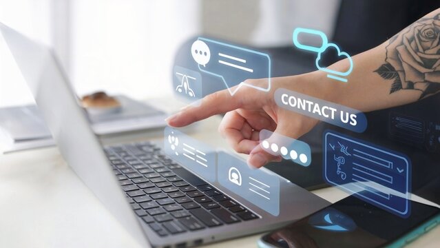 A photograph of a person's hand with a rose tattoo on his forearm using a laptop and smartphone. There is a digital holographic interface showing a chat box and various icons, including a Contact Us b - Powered by Adobe