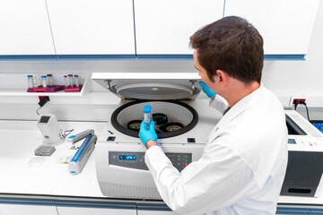 Laboratory technician using refrigerated centrifuge machine in blood bank, Benchtop Centrifuges,...