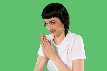 Playful Woman Rubbing Her Hands, Hands Clasped, Looking Mischievous Against Bright Background