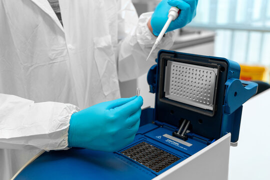 Loading a DNA tube into a PCR (polymerase chain reaction) thermocycler machine in a bioscience laboratory. PCR Thermal Cyclers. Coronavirus (COVID-19) treatment.