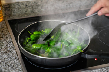 Tapas Klassiker Gebratene Pimientos de Padron werden in einer schwarzen Pfanne gebraten