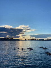 Fototapeta premium Kayaks in ocean at sunset in front of city skyline