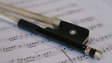 Close up photo of cello bow and sheet music; 16x9 format