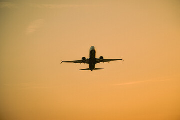 Airplane silhouette during takeoff at sunset with a golden sky