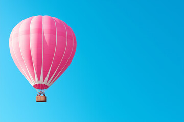 Naklejka premium A vibrant pink hot air balloon gliding high in a clear blue sky on a sunny day