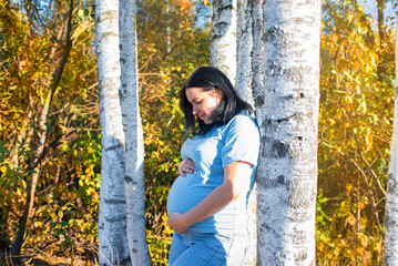 42 year old pregnant woman in autumn park, standing near birch trees. pregnancy after 40, third...