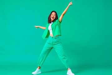 Full body photo of pretty positive malaysian person have fun dancing clubbing isolated on shine emerald color background