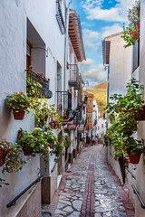 Narrow street with pots of geraniums hanging on the walls in the town of Castril, Granada.