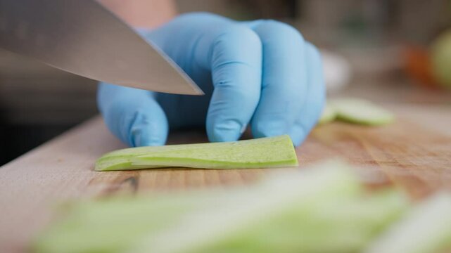 Chef Cuts Zucchini Vegetable On A Wooden Cutting Board In Restaurant Kitchen