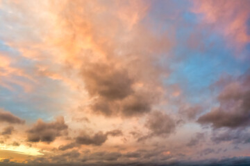 A beautiful sky tinted by the sun leaving vibrant shades of gold, pink, blue and multicolored. Clouds in the twilight evening and morning sky. Cloudy sky background in the evening, and during the day.