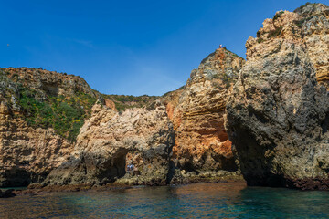 Colorful cliffs and rock formations along the Algarve coastline, Portugal, viewed from the clear waters of the Atlantic.