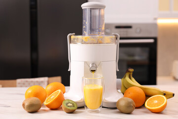 Modern juicer, fresh fruits and glass on white marble table in kitchen