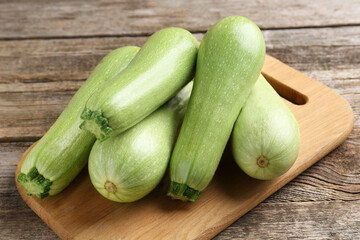 Board with fresh zucchinis on wooden table, closeup