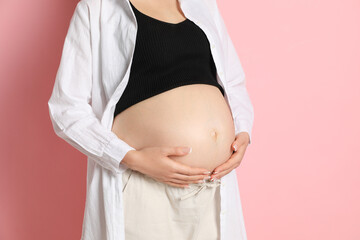 Young pregnant woman on pink background, closeup