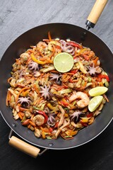 Stir-fry sea food in wok on grey textured table, top view